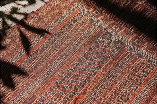 床に敷かれたヴィンテージラグに葉っぱの影が映っている様子